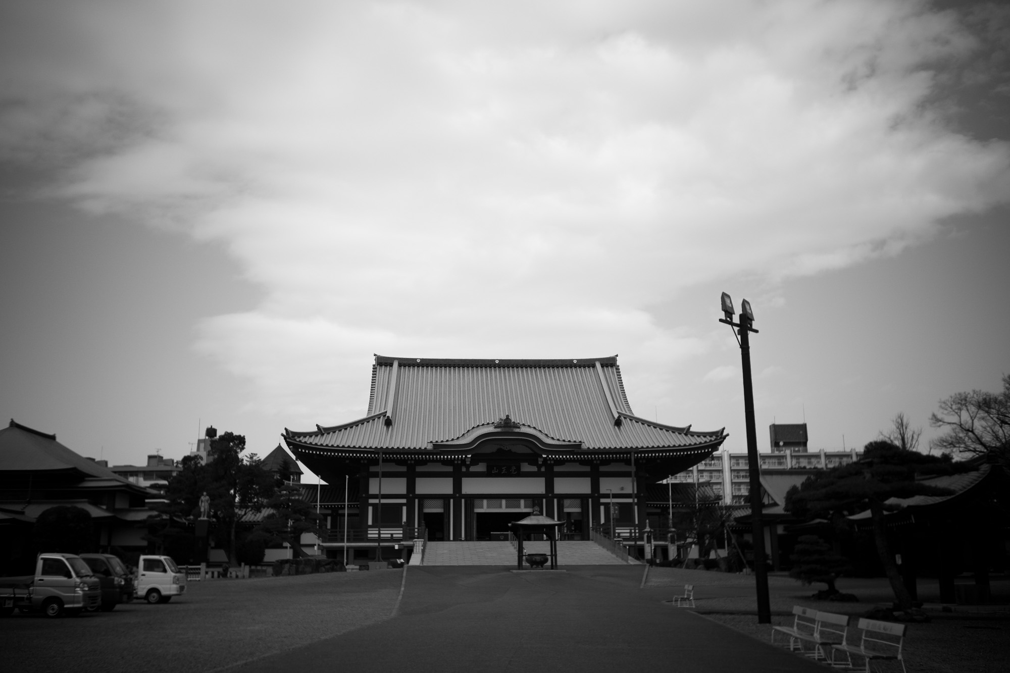 KAKUOZAN NITTAIJI //【LEICA M10-P ASC 100 Edition + Elmar 35mm 1938年製】 覚王山日泰寺　覚王山日泰寺 （かくおうざん にったいじ） は、愛知県名古屋市千種区法王町にある超宗派の寺院である。　愛知県名古屋市千種区法王町1-1　 タイ王国から寄贈された仏舎利（釈迦の遺骨）を安置するために、創建された　「覚王」とは、釈迦の別名。また「日泰」とは、日本とタイ王国を表している。日泰寺には、その真正について考古学的な裏付けがされている仏舎利が納められている上、インドでそのような仏舎利が発掘され、タイ王国を経由して、その一部が日本へと譲られる1900年前後の過程では、真身舎利（真正仏舎利）への信仰や敬いに加え、安置場所などを巡る日本仏教界内の激しい争いもあり、日本国内で大きな話題となったが、現在における日泰寺の知名度は高いものではない　一方、日本仏教界における特別な位置づけを反映し、真宗大谷派、浄土真宗本願寺派、曹洞宗等複数の宗派が合同で設けた超宗派の単立寺院であり、各宗派（現在19宗派が参加）の管長が、三年交代で住職を務めている[新聞 2]。ただし境内北側に設置されている僧堂は、曹洞宗が管轄している。住職は宗派の違うお経を上げることもあるという。真身舎利（真正仏舎利）は、本堂のある境内からやや離れた「奉安塔」の中に安置されている。ただ、一般参拝者の拝観が認められていないことは、自らの遺骨を通じ、人々の修行や功徳に向かう心を支えようとした仏陀の教えに反しているとの指摘もされている境内には真身舎利を日本に寄贈したラーマ5世の像もあり、在日タイ大使は誕生日に参拝するのが習わしになっている。また在日タイ人もしばしば参拝に訪れるという。毎月21日に、境内と約600メートルの参道に日用雑貨、生鮮食品、外食の屋台が100店ほど出店して、多くの人で賑わう。起源と歴史1898年（明治31年） - 仏教開祖釈迦（ゴータマ・シッダルータ）の遺骨、真身舎利が発見される。インドのピプラーワー（英語版）村（仏陀の生まれたカピラヴァストゥの跡という説がある）において、イギリス人ウイリアム・C・ペッペによって水晶製の舎利容器が発掘され、古代文字の解読の結果判明。1899年（明治32年） - 舎利が、英国からシャム国（現在のタイ王国）へ譲渡される。1900年（明治33年） - 舎利が、シャム国国王ラマ五世（ラーマ5世）から日本国民へ贈られた。1904年（明治37年） - 舎利と黄金の釈迦像を奉安するため、覚王山日暹寺（にっせんじ）として創建[新聞 1]。1914年（大正3年） - 伽藍を整備。1949年（昭和24年） - シャム国のタイ王国への改名に合わせて日泰寺に改名。