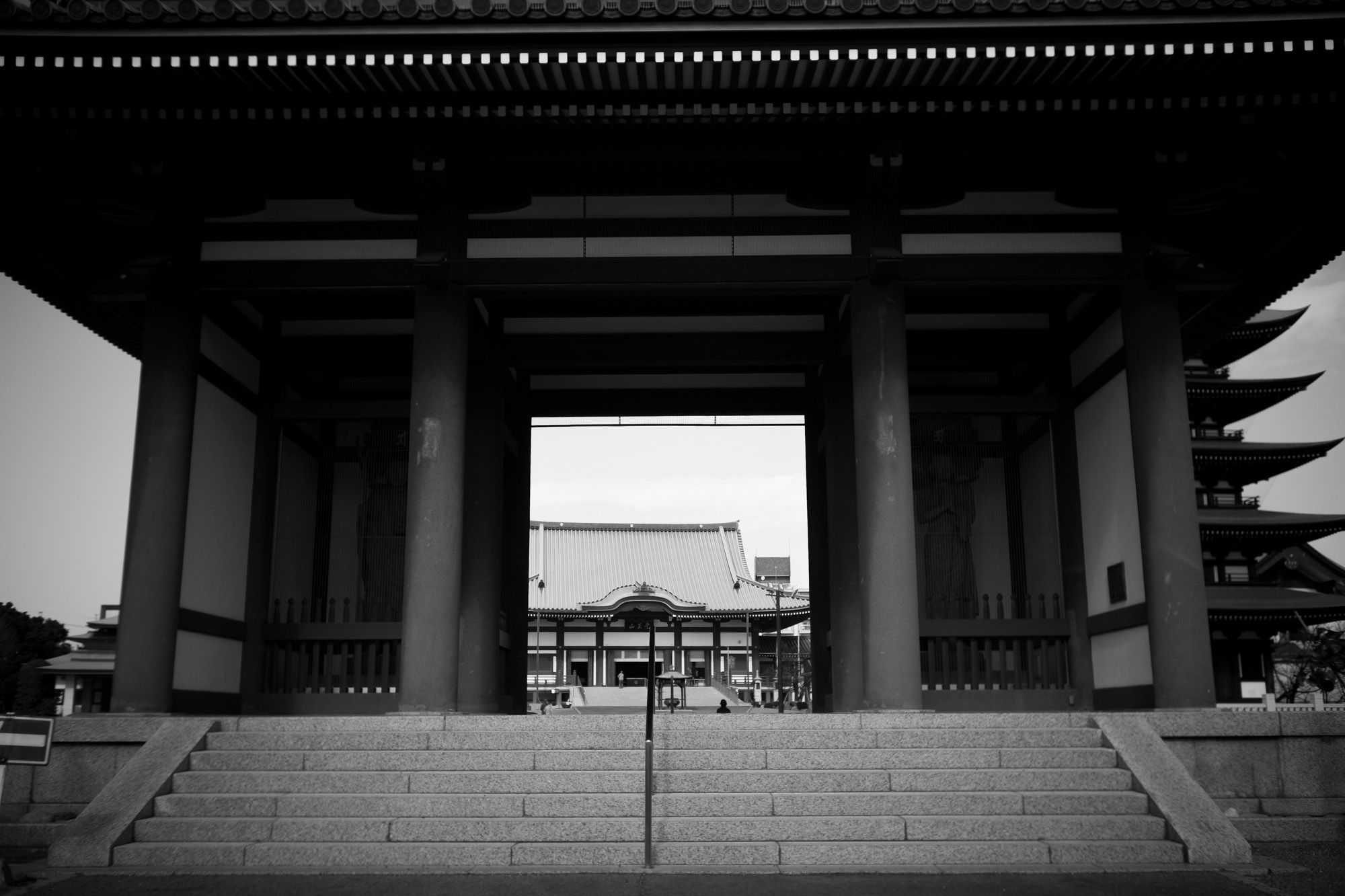 KAKUOZAN NITTAIJI //【LEICA M10-P ASC 100 Edition + Elmar 35mm 1938年製】 覚王山日泰寺　覚王山日泰寺 （かくおうざん にったいじ） は、愛知県名古屋市千種区法王町にある超宗派の寺院である。　愛知県名古屋市千種区法王町1-1　 タイ王国から寄贈された仏舎利（釈迦の遺骨）を安置するために、創建された　「覚王」とは、釈迦の別名。また「日泰」とは、日本とタイ王国を表している。日泰寺には、その真正について考古学的な裏付けがされている仏舎利が納められている上、インドでそのような仏舎利が発掘され、タイ王国を経由して、その一部が日本へと譲られる1900年前後の過程では、真身舎利（真正仏舎利）への信仰や敬いに加え、安置場所などを巡る日本仏教界内の激しい争いもあり、日本国内で大きな話題となったが、現在における日泰寺の知名度は高いものではない　一方、日本仏教界における特別な位置づけを反映し、真宗大谷派、浄土真宗本願寺派、曹洞宗等複数の宗派が合同で設けた超宗派の単立寺院であり、各宗派（現在19宗派が参加）の管長が、三年交代で住職を務めている[新聞 2]。ただし境内北側に設置されている僧堂は、曹洞宗が管轄している。住職は宗派の違うお経を上げることもあるという。真身舎利（真正仏舎利）は、本堂のある境内からやや離れた「奉安塔」の中に安置されている。ただ、一般参拝者の拝観が認められていないことは、自らの遺骨を通じ、人々の修行や功徳に向かう心を支えようとした仏陀の教えに反しているとの指摘もされている境内には真身舎利を日本に寄贈したラーマ5世の像もあり、在日タイ大使は誕生日に参拝するのが習わしになっている。また在日タイ人もしばしば参拝に訪れるという。毎月21日に、境内と約600メートルの参道に日用雑貨、生鮮食品、外食の屋台が100店ほど出店して、多くの人で賑わう。起源と歴史1898年（明治31年） - 仏教開祖釈迦（ゴータマ・シッダルータ）の遺骨、真身舎利が発見される。インドのピプラーワー（英語版）村（仏陀の生まれたカピラヴァストゥの跡という説がある）において、イギリス人ウイリアム・C・ペッペによって水晶製の舎利容器が発掘され、古代文字の解読の結果判明。1899年（明治32年） - 舎利が、英国からシャム国（現在のタイ王国）へ譲渡される。1900年（明治33年） - 舎利が、シャム国国王ラマ五世（ラーマ5世）から日本国民へ贈られた。1904年（明治37年） - 舎利と黄金の釈迦像を奉安するため、覚王山日暹寺（にっせんじ）として創建[新聞 1]。1914年（大正3年） - 伽藍を整備。1949年（昭和24年） - シャム国のタイ王国への改名に合わせて日泰寺に改名。