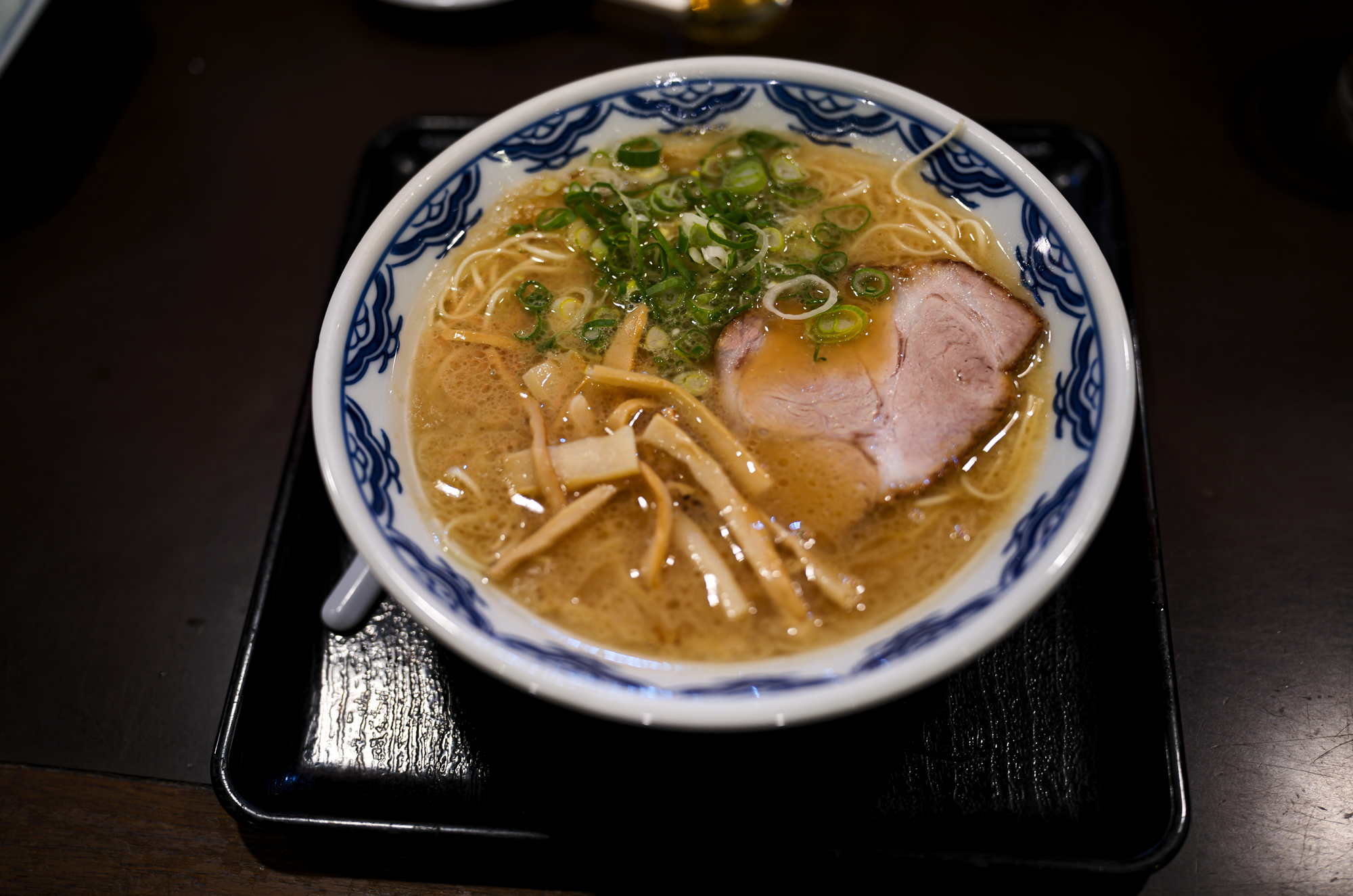 博多麺房 赤のれん 西麻布本店 タモリ 赤のれん タモリ 西麻布交差点 釜炊きとんこつ  東京都 港区 西麻布 3-21-24 第五中岡ビル１Ｆ 釜炊きとんこつ「とれたての味」 「濃厚な豚骨のコクと旨み」と「醤油ダレのキレ」店内に大型の五右衛門釜を持ち込み、毎日一日かけて取るスープはコクと旨みがあって「コッテリ」ながらも、醤油ダレをきかせることにより後味が「サッパリ」になるように仕上げております。厳選した豚骨の部位だけを使用し、丁寧に下処理を行い濃厚な旨みだけを抽出。100％純豚骨スープをお楽しみください。「平打ち極細麺」初代、津田茂氏が考案した極細平打ち極細麺。一般的な麺の断面が丸や角に比べて薄く平べったくなっており、サクッとした食感とスープとの絡みが良いのが特徴です。麺の硬さは、粉おとし・ハリガネ・バリカタ・固め・普通・ヤオ麺の6種類があり、硬さによって食感、小麦粉の風味など大きく変化します。替え玉などで食べ比べるのも楽しいかと思います。本物のラーメンを召し上がりませんか？毎日一日かけて五右衛門釜でとるとんこつスープはコクと旨みがあって後味さっぱり。秘伝の醤油ダレを加えたスープが極細平打麺にからむ絶妙の味です。釜炊きとんこつ「とれたての味」をご賞味ください。「由来」福岡は箱崎で津田茂氏が開業した博多ラーメン赤のれんは「腰が強い平打ち細麺］と「こってり味でさっぱり感のある醤油仕立てのとんこつラーメン」が造りだす絶品の旨さが大人気となり、昭和50年頃はその味は博多随一と評判でした。この地に赤のれんが誕生した由来は、博多赤のれんに弟子入りした先代が六本木付近に創業の場所を求めたことにあります。六本木から西麻布にかけてこのとおり一帯は、昔から「元すりとおり」と呼ばれ地元の人たちから商売は難しい場所と見られていました。西麻布に創業し40年、ひたすらに本物の味を追及しお客様の求める旨い味づくりに専念してまいりました。今も変わらず商いができますのもお客様の暖かい支持の賜物と感謝いたしております。 https://www.akanoren.com/