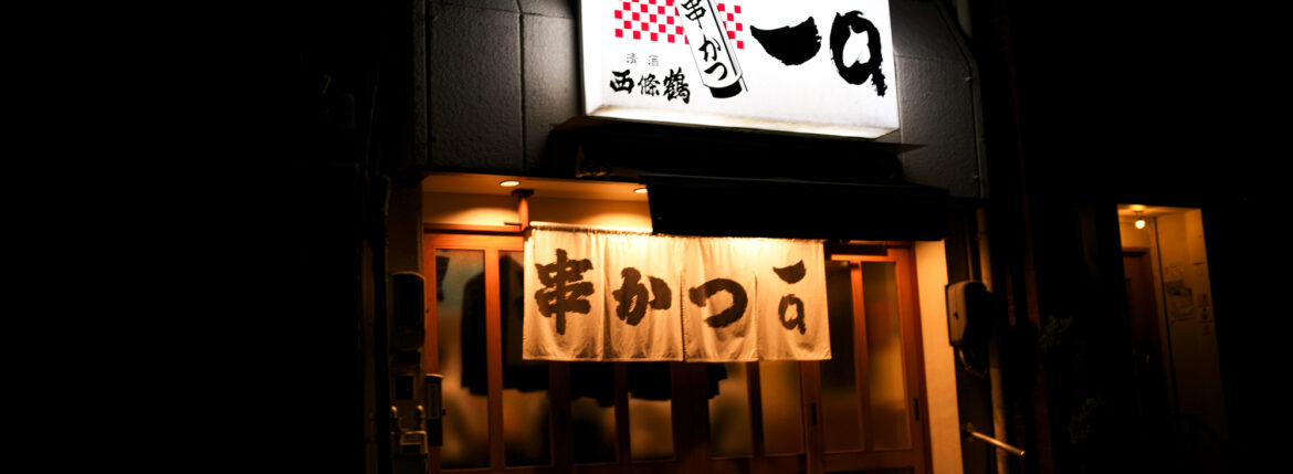 串かつ 一口 〒722-0045 広島県尾道市久保2丁目10−10 尾道『串かつ 一口』串かつは音が命と語る二代目。老舗の絶品魚介串かつ 平日も満員御礼、尾道には一晩の営業で2回転もする串かつ店があります。店の名は『串かつ 一口』。創業は1964年と古く、歴史ある尾道の街らしさを感じる酒場。瀬戸内で水揚げされる魚介類など地元の食材をつかった串かつは、一度食べたらきっと忘れられなくなる。串かつ 広島県の尾道には、それはもう絶品の魚介類の串かつを楽しませてくれる名店があります。尾道で58年続いてきた『串かつ一口』。尾道の飲み屋街「新開」にあります。2018年まで別の店舗で営業をしてきましたが、移転して現在の姿になりました。二代目の大将を中心に、三代目らが手伝う家族経営の店 はも:250円、えび:310円、とり貝:310円、たこ:240円、いわし:220円、貝柱:220円、くじら:240円、にし:220円、きす:240円。あさり:880円、あなご一本:990円、串かつ:130円など。きすは尾道の名産です。一口には「必ずこれを頼む」という料理が常連さんそれぞれにありますが、キスも大変人気の“種”。繊細な旨味を引き出す塩・レモンをかけていただきます。薄い衣はパリッとしており、続けてふかふかの身が口の中で溶け広がります。思わず目を見開く美味しさ。愛知 名古屋 Alto e Diritto altoediritto アルトエデリット