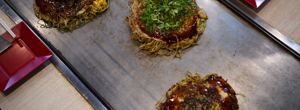 三國志　〒721-0907 広島県福山市春日町６丁目９−１０ oko_sangoku 広島名物お好み焼き、鉄板焼き 広島名物 広島風お好み焼き、多くの種類のトッピングの組み合わせで、 オリジナルお好み焼きをお楽しみ下さい。広島県 福山市 福山東インターチェンジから 車で約１０分 広島 お好み焼の お店。キャベツたっぷり　生麺使用　数種のスパイスが隠し味　鉄板で熱々のお好み焼を是非！　冷凍お好み焼販売中　ご家庭にストック　いつでも美味しい。「お好み焼・鉄板焼　三國志」（福山市春日町6-9-10、藤井啓文代表）はこのほど、冷凍お好み焼きを開発して販売を始めた。 　コロナ禍で店内での飲食が減る中、スーパーやコンビニでは冷凍食品の需要が増えていることから、お好み焼きの冷凍販売を思いついたという。「二四時間、出来たての味を楽しんでほしい」と昨年から開発に乗り出した。「レンジで温めた際、店内で食べるお好み焼きと同じ状態になるよう工夫した」と藤井代表。店内で提供する物と同じ材料で焼き上げ、専用の機械で急速冷凍する。レンジでの加熱を考慮し、焼く時間を通常の七─八割に抑えて調整を重ねたという。 　肉玉（760円）、イカ・エビ・肉玉入りの「三國志スペシャル」（1040円）をはじめ、イカ天肉玉（880円）、チーズ肉玉（860円）など約10種類がある。 　レンジで温める時間は七分前後。肉玉の場合は裏返して三分、表にして四分温める。最後に別袋入りのソースをかければ完成。同店ならではの、飽きのこないやさしい味が楽しめる。常連客からは「店で食べるのと同じくらいおいしかった 「冷凍庫にストックしておいて、食べたい時に食べられるのがうれしい」といった声が寄せられているとか。藤井代表は「自宅用やお土産にぜひどうぞ。準備が整えば、地方発送も始めます」と話す。 　なお、夏をめどに価格の改定を行う予定。また一度に10枚以上購入する場合は、一週間前までに予約が必要。 　ホルモン焼き（860円）や焼きそば（710円）など鉄板焼きメニューの冷凍商品も用意している。