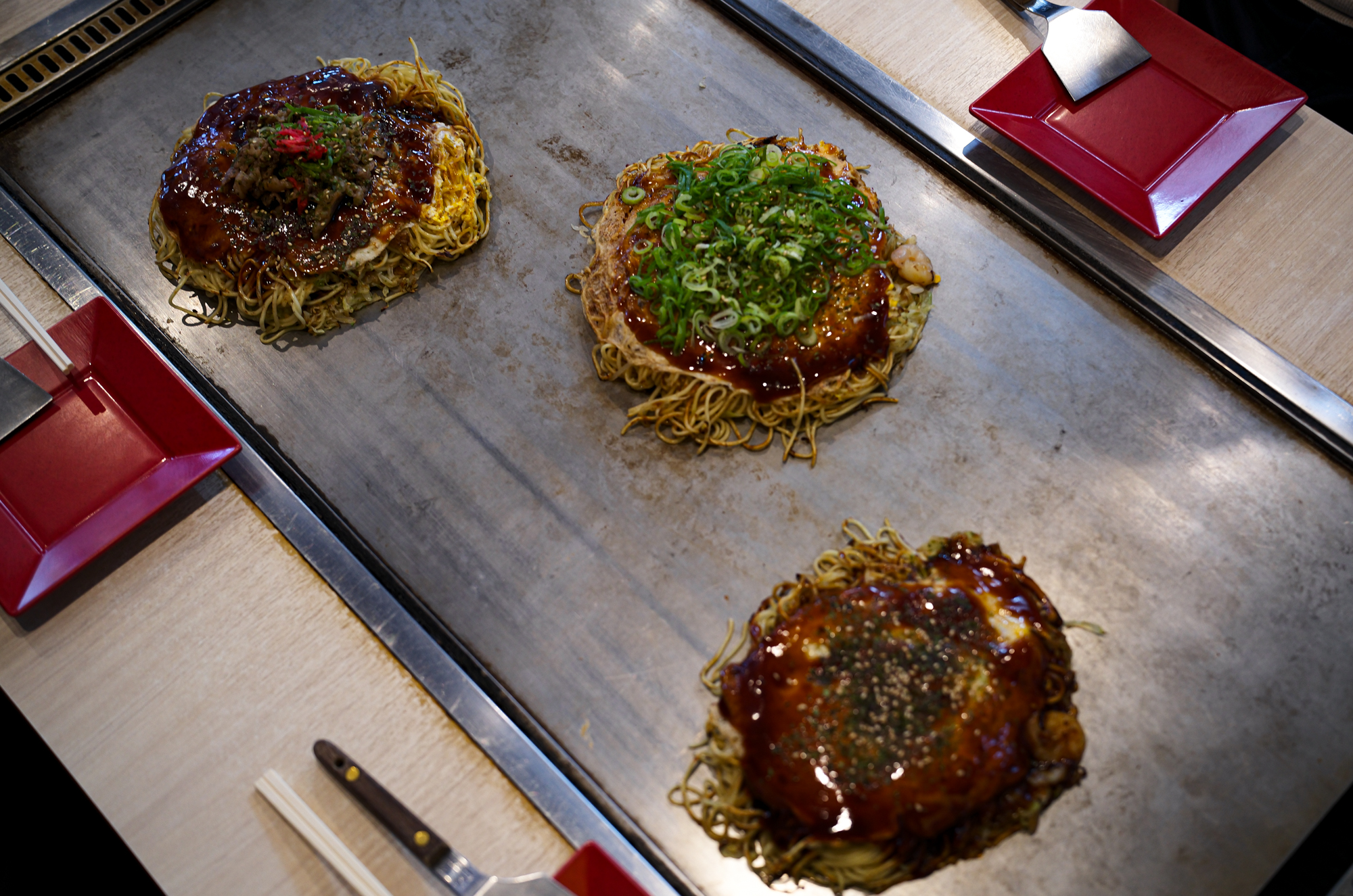 三國志　〒721-0907 広島県福山市春日町６丁目９−１０ oko_sangoku  広島名物お好み焼き、鉄板焼き  広島名物 広島風お好み焼き、多くの種類のトッピングの組み合わせで、 オリジナルお好み焼きをお楽しみ下さい。広島県 福山市 福山東インターチェンジから 車で約１０分 広島 お好み焼の お店。キャベツたっぷり　生麺使用　数種のスパイスが隠し味　鉄板で熱々のお好み焼を是非！　冷凍お好み焼販売中　ご家庭にストック　いつでも美味しい。「お好み焼・鉄板焼　三國志」（福山市春日町6-9-10、藤井啓文代表）はこのほど、冷凍お好み焼きを開発して販売を始めた。 　コロナ禍で店内での飲食が減る中、スーパーやコンビニでは冷凍食品の需要が増えていることから、お好み焼きの冷凍販売を思いついたという。「二四時間、出来たての味を楽しんでほしい」と昨年から開発に乗り出した。「レンジで温めた際、店内で食べるお好み焼きと同じ状態になるよう工夫した」と藤井代表。店内で提供する物と同じ材料で焼き上げ、専用の機械で急速冷凍する。レンジでの加熱を考慮し、焼く時間を通常の七─八割に抑えて調整を重ねたという。 　肉玉（760円）、イカ・エビ・肉玉入りの「三國志スペシャル」（1040円）をはじめ、イカ天肉玉（880円）、チーズ肉玉（860円）など約10種類がある。 　レンジで温める時間は七分前後。肉玉の場合は裏返して三分、表にして四分温める。最後に別袋入りのソースをかければ完成。同店ならではの、飽きのこないやさしい味が楽しめる。常連客からは「店で食べるのと同じくらいおいしかった 「冷凍庫にストックしておいて、食べたい時に食べられるのがうれしい」といった声が寄せられているとか。藤井代表は「自宅用やお土産にぜひどうぞ。準備が整えば、地方発送も始めます」と話す。 　なお、夏をめどに価格の改定を行う予定。また一度に10枚以上購入する場合は、一週間前までに予約が必要。 　ホルモン焼き（860円）や焼きそば（710円）など鉄板焼きメニューの冷凍商品も用意している。