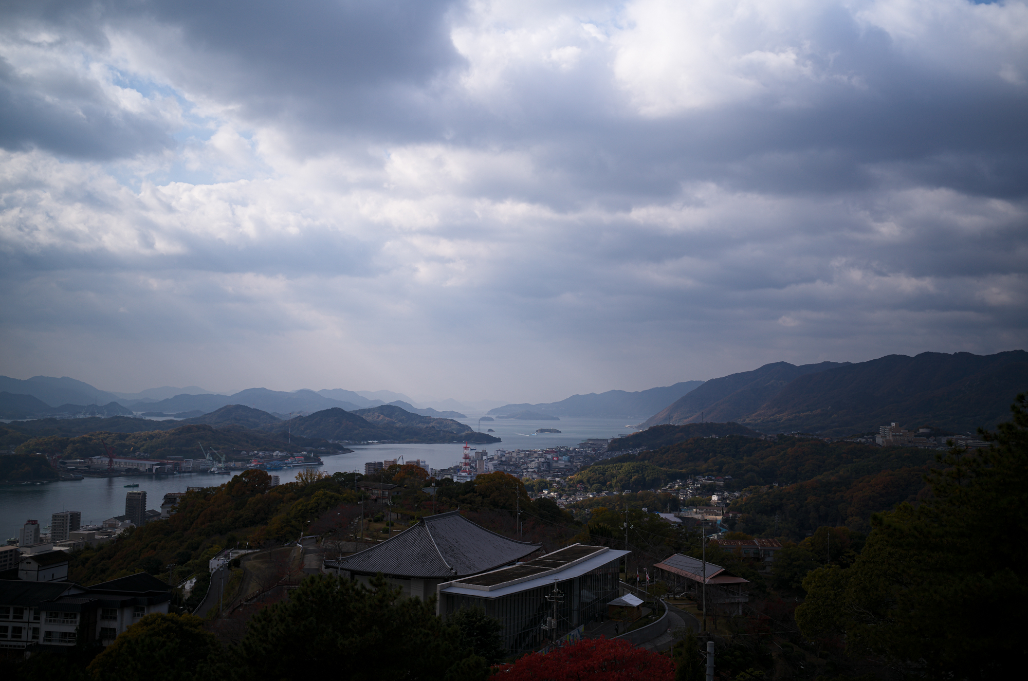 尾道 大宝山 千光寺　〒722-0033　尾道市東土堂町15-1　TEL：0848-23-2310　URL https://senkouji.jp/ 大宝山権現院千光寺は標高140m、尾道港を一望する大宝山の中腹にあり、（大同元年・806年）弘法大師の開基で中興は多田満仲公と伝えられています。珍しい舞台造りの本堂(貞享3年・1686年)は別名「赤堂」とも呼ばれ、林芙美子も放浪記の中で「赤い千光寺の塔が見える」と書いています。大宝山 千光寺は、広島県尾道市の旧市街に位置しています。尾道へのお越しには、自動車、高速乗合バス、新幹線、飛行機が主な交通手段となります。最寄の駅は新幹線『新尾道駅』もしくは在来線『尾道駅』となります。大宝山権現院千光寺は標高140m、尾道港を一望する大宝山の中腹にあり、（大同元年・806年）弘法大師の開基で中興は多田満仲公と伝えられています。開基は平安時代の始め大同元年（806年）で、後に源氏の名将多田満仲の中興と伝えている。境内中央の巨岩「玉の岩」は昔この岩の頂に如意宝珠があって、夜毎に海上を照らしていたのでこの地を「玉の浦」と呼ぶとか。玉の岩の右には朱塗りの本堂、左には龍宮造りの鐘楼を配して、尾道の風光のかなめをなしている。本堂は貞享三年（1686年）の建立で、この地方には珍しい舞台造り、堂内に置かれた須弥壇は応永から永享（1394～1440年）頃の作で、和様に唐様を加味した形式で、ここに安置された本尊は秘仏の千手観世音菩薩。鐘楼の鐘は除夜の鐘でもおなじみのもの「音に名高い千光寺の鐘は一里聞こえて二里ひびく」と俚謡にまでうたわれている。本堂までの長い階段の左右には、かつて若杉慧の「野の仏」にも紹介された古い石仏や除虫菊の創始者上山英一郎翁の頌徳碑や児玉不揺の筆塚などもある。この寺の眺望は我が国随一といわれ山頂から八合目あたりを巡る「文学のこみち」は、尾道の風光を愛でた文人墨客の作品を天然の岩に刻んだ遊歩道である。中国観音霊場第十番札所、備後西国観音霊場第七番札所本尊千手観世音菩薩は聖徳太子の御作と伝えられ、三十三年に一度開帳の秘仏。昔から「火伏せの観音」と称せられ、火難除けに霊験あらたかで、今は諸願成就の観音様としてお詣りが絶えません。尾道は往古より港町として栄え、風光明媚なことから多くの文人墨客が訪れています。中でも頼山陽は「六年重ねて来たる千光寺」と漢詩にも詠んでいます。千光寺にまつわる“尾道で最も有名な伝説”が『玉の岩』伝説です。千光寺の象徴ともいえる“玉の岩”の天頂部には、その昔光る玉がありました。尾道には“玉”にかかわる地名もあり、千光寺の名前の由来もここからきていると聞きます。